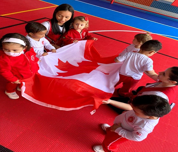 Alunos e professora da Maple Bear com a bandeira do Canadá